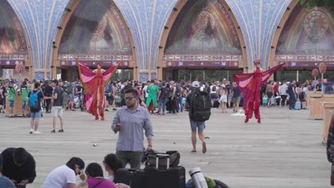 Caminantes-En-Zancos-Actuando-Alrededor-De-La-Gente-Que-Espera-En-Las-Puertas-De-Entretenimiento-En-Tomorrowland-Celebrada-En-Auge,-Bélgica