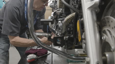 Automotive-trade-school-student-mechanic-works-on-a-motorcycle-engine-in-the-auto-garage-slider-shot