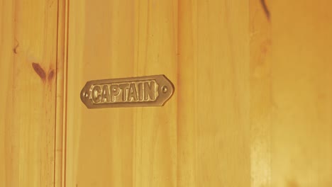 Brass-metal-Captain-sign-mounted-on-wooden-door