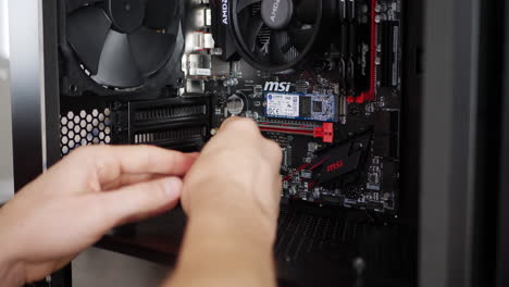 Un-Técnico-De-Reparación-De-Computadoras-Instalando-Y-Conectando-Cables-De-Encabezado-De-Ventilador-En-Una-Placa-Base-Para-Juegos-Msi-En-Un-Ensamblaje-De-Construcción-De-Caja-De-PC