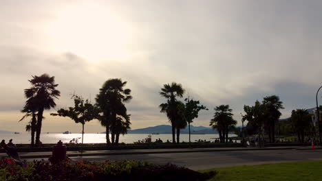 Las-Sombras-De-La-Puesta-De-Sol-De-Ciclistas-Y-Personas-En-Bicicleta-Van-Desde-La-Carretera-Del-Centro-Del-Puente-De-Burard,-La-Playa-De-La-Puesta-De-Sol,-La-Bahía-Inglesa-Hasta-El-Parque-Stanley-Mientras-Los-Autos-Están-Restringidos-Debido-A-La-Pandemia-De-Covid-19