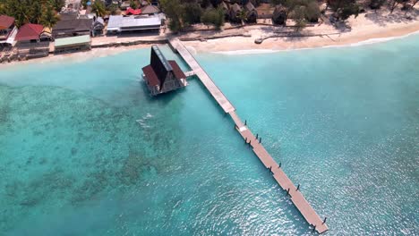 Aerial-top-down-shot-of-beautiful-Gili-Meno-Island-with-turquoise-clear-water-and-wooden-footbridge-in-summer