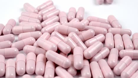 Close-up-of-the-rotation-soft-pink-pills-or-capsules-on-white-background