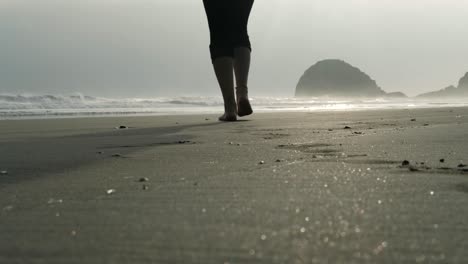 woman-walking-barefoot-on-sand-at-sunset