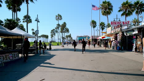 Pedestrians-Casually-Strolling-down-Boardwalk-on-Sunny-Summer-Day-in-Venice,-California