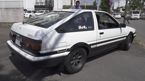 Moving-Shot-of-a-Man-Parking-His-Retro-White-Toyota-AE86