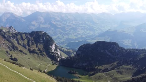 Lago-Azul-Profundo-De-Las-Montañas-En-Un-Jugoso-Valle-Verde-Rodeado-De-Bosque-En-Suiza