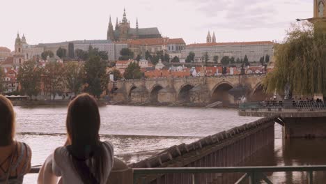 Tourists-Looking-At-Charles-Bridge-From-Rivers-Edge-In-Prague