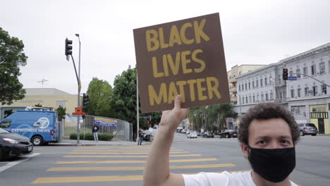Junger-Weißer-Mann-In-Maske-Hält-Black-Lives-Matter-Schild-Bei-Der-Kundgebung-Vor-Die-Kamera