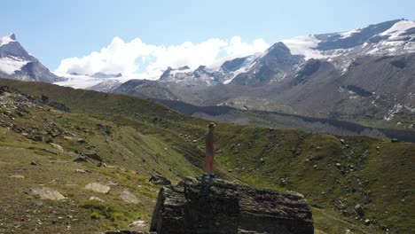 A-young-man-is-standing-by-himself-on-a-cliff,-taking-in-the-epic-and-amazing-view-in-front-of-him-in-Zermatt,-Switzerland
