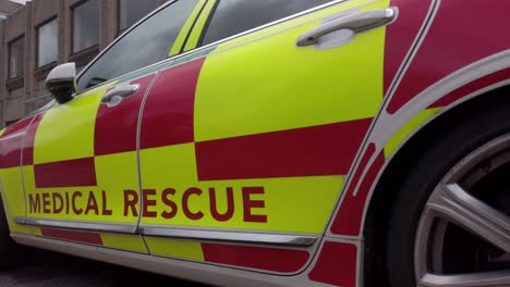 UK-NHS-emergency-rapid-response-medical-rescue-service-car-outside-hospital-pan-right-low