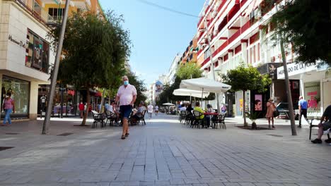 Gesperrte-Aufnahme-Von-Menschen-Mit-Schutzmasken-In-Einer-Fußgängerzone-In-Benidorm,-Einem-Großen-Touristenort-An-Der-Spanischen-Mittelmeerküste