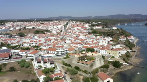 Flying-in-over-the-beautiful-white-houses-of-Vila-Nova-de-Milfontes,-Portugal-during-mid-day