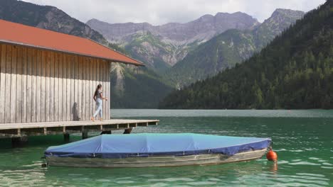 Girl-poses-in-front-of-fisherhouse-at-Lake-Plansee,-Austria