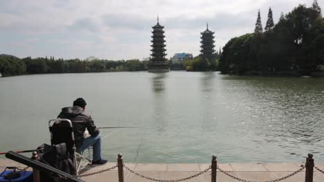 Mann,-Der-Auf-Mond-Und-Sonne-Fischt,-Ragt-See-In-Guilin-China-Hoch