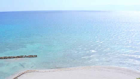 Aerial-view-over-turquoise-sea,-beach-and-the-Puntarena-resort,-in-Bani,-Punta-Arena,-Domienican-republic,-Caribbean-America---Reverse,-drone-shot