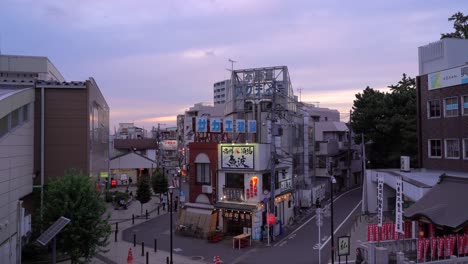 Typical-scenery-in-calm-residential-Tokyo,-Japan-neighborhood-at-dusk-with-illuminated-shops-and-people-going-home---wide-open-locked-off-view