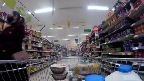 Inside-supermarket-shopping-cart-pushing-trolley-down-milk-aisle-as-customers-shop-during-corona-virus-pandemic