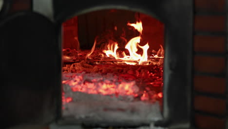 Wood-Fire-Burning-Inside-A-Brick-Stone-Oven-In-A-Bakery---sliding-shot