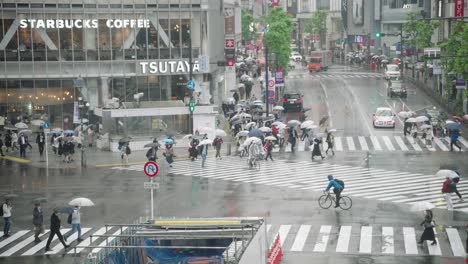 Gente-Con-Paraguas-Caminando-En-El-Cruce-De-Shibuya-En-Un-Día-Lluvioso-En-Tokio,-Japón