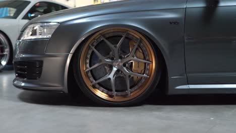 Silver-Golden-Alloy-Wheel-Rim-on-Luxury-Car-in-Show-Room,-Dolly-Shot-Close-Up