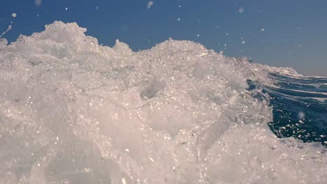 Low-angle-perspective-of-water-splash-on-sea-surface-behind-speedboat