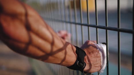 Portrait-of-Caucasian-sports-man-leaning-on-urban-metal-fence-while-rest-after-active-training