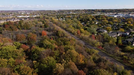 Aerial-of-train-tracks-surrounded-by-forest-in-fall-colors