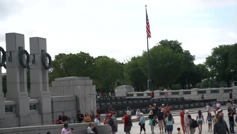 Multitudes-De-Turismo-Con-La-Bandera-Nacional-De-Estados-Unidos-Ondeando-Contra-El-Cielo-Brillante-En-El-Memorial-De-La-Segunda-Guerra-Mundial-En-Washington-DC,-Estados-Unidos