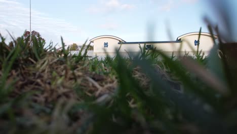 A-view-of-a-building-through-grass-as-seen-by-a-parked-or-landed-drone