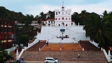 Drone-Flying-Up-A-Lush-Hillside-With-View-Of-Mary-Immaculate-Conception-Church-In-Panjim,-Goa,-India---Aerial-Drone-Shot