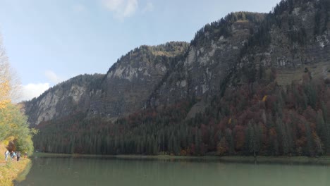 Tilting-up-from-the-water-to-the-mountains-above-Lac-de-Montriond,-during-camping-van-trip-in-Morzine,-French-Alps