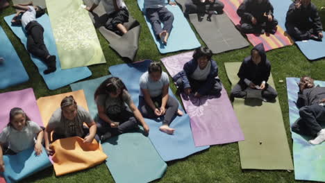 Elementary-Students-Doing-Yoga-on-Colorful-Mats,-Grass-at-School,-Shot-From-Above