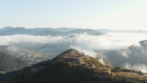 Takeda-Castle-Ruins-Aerial-Reveal,-Clouds-Over-Valley-in-Morning