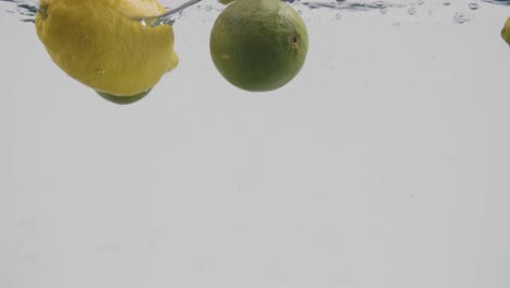 Limones-Enteros-Y-Limas-Salpicando-Agua