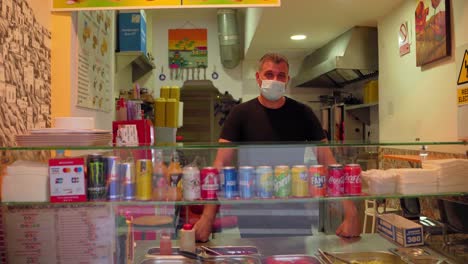 Food-Store-Owner-Wearing-Mask-While-Waiting-For-Customers-In-Malaga,-Spain---Covid-19-Crisis---forward-shot