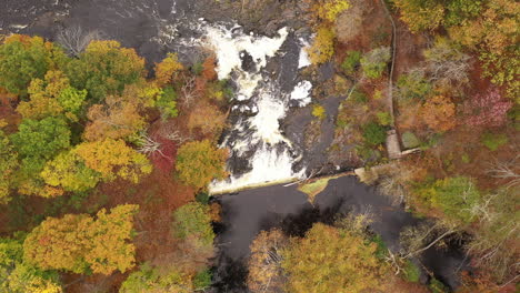 A-top-down-shot-directly-above-a-waterfall,-surrounded-by-colorful-fall-foliage-in-upstate-NY