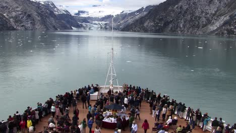 Tourists-on-the-bow-of-a-cruise-ship-in-Glacier-Bay-National-Park-Alaska,-looking-at-the-John-Hopkins-Glacier-and-enjoying-the-landscape