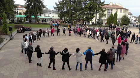Orbit-aerial-shot-of-people-dance-in-circle-at-town-square---celebration