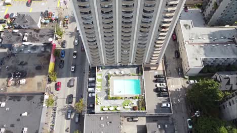Aerial-dolly-roll-fly-over-Vancouvers-davie-street-roadside-tropical-Sandman-Hotel-swimming-pool-drone-camera-rise-to-rooftop-sign-with-the-Gay-pride-flag-birds-eye-view-of-outdoor-private-basin-1-2
