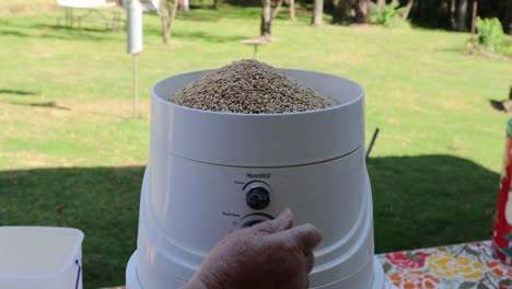 Woman's-hands-making-the-settings-on-a-personal-sized-electric-wheat-mill