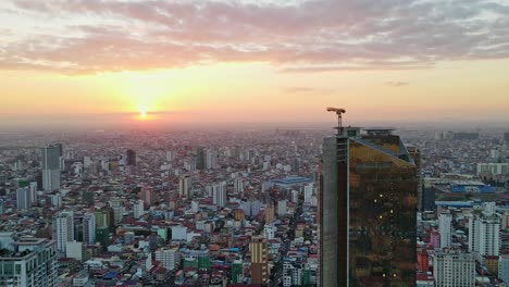 Majestätische-Luftdrohnenaufnahme,-Die-Ein-Wunderschönes-Stadtbild-Und-Wolkenkratzer-In-Phnom-Penh-Während-Des-Epischen-Sonnenuntergangs-In-Kambodscha-Zeigt