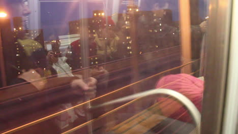 Subway-Reflection-of-Commuters-in-NYC,-Moving-Above-Ground-Amidst-Buildings-and-Bridges