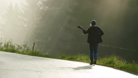 A-musician-is-walking-by-the-side-of-a-road-playing-the-guitar