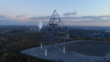 Aerial-drone-fly-past-people-on-viewing-platform,-Tetraeder-Bottrop,-sunset