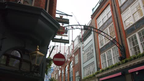 Smooth-slow-motion-trucking-gimbal-shot-of-a-Green-King-Pub-revealing-Carnaby-Streets-entrance-sign,-London