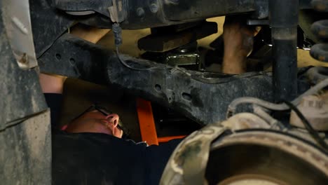 A-mechanic-lays-under-a-vehicle-making-repairs-to-it