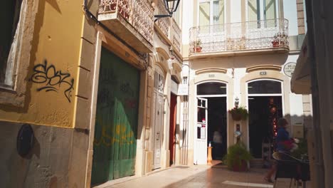 Portugal-Algarve-Loule-Schmale-Steinpflasterstraße-Mit-Typischen-Geschäften-Und-Fußgängern,-Die-Bei-Morgensonne-4k-Spazieren-Gehen