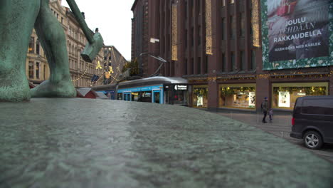 Straßenbahn,-Die-Hinter-Der-Verwitterten-Bronzestatue-Der-Drei-Schmiede-Hält