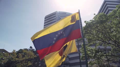 Bandera-Venezolana-Junto-A-La-Bandera-Del-Municipio-De-Chacao-Ondeando-En-La-Plaza-Francia,-También-Conocida-Como-Plaza-Altamira,-En-Chacao,-Caracas,-Venezuela